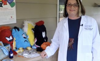A Sanford Health provider poses with plush toys showing different emotions.