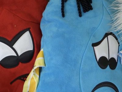 Red and blue fuzzy pillows with faces showing emotions of anger and sadness.
