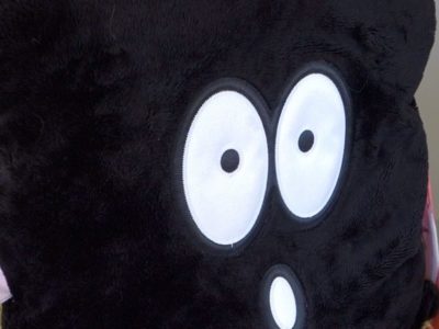 Black fuzzy pillow with face with wide open eyes and mouth showing the emotion of fear.