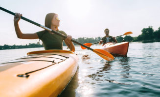 Young couple kayaking on lake together and smiling.