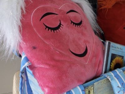 Pink fuzzy pillow with heart-shaped face showing emotion of love.