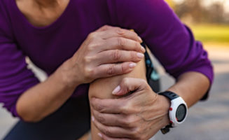 Senior Woman Runner Hold Her Sports Injured Knee Outdoors.