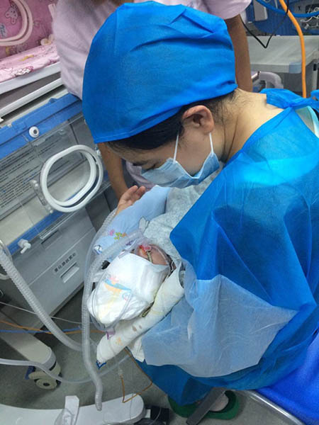 A woman in PPE holds her tiny baby in the NICU in Kunming, China.