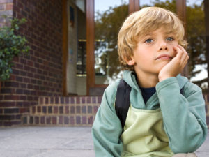 Childhood anxiety or worry. Thoughtful boy sitting outdoors.