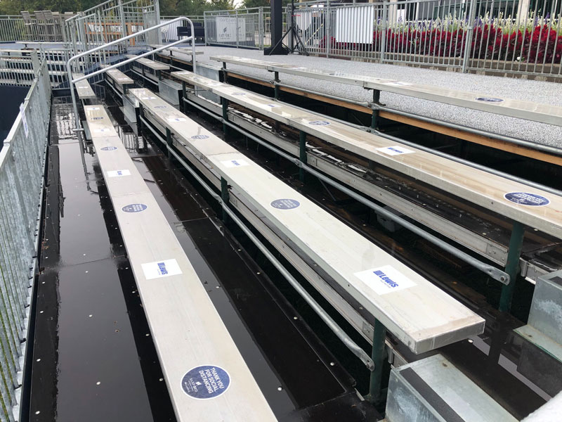 Empty stadium bleacher seats have stickers every few feet about social distancing.