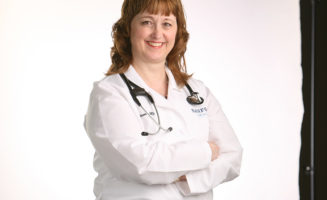 Dr. Shirlene Smook smiles and stands in a white coat and stethoscope.