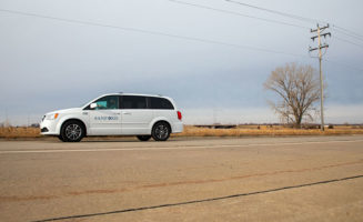 A Sanford Health minivan courier carries mail and vaccines down a rural road in winter.