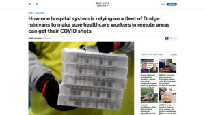 Business Insider website screen shot with closeup of healthcare worker in gown with gloves carrying a stack of COVID vaccine trays, under headline "How one hospital system is relying on a fleet of Dodge minivans to make sure healthcare workers in remote areas can get their COVID shots"
