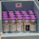 Purple-capped vials of COVID-19 vaccine sit in a blue tray at Sanford Health.