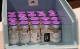 Purple-capped vials of COVID-19 vaccine sit in a blue tray at Sanford Health.