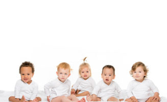 Happy multicultural babies sit in a row on a white background.