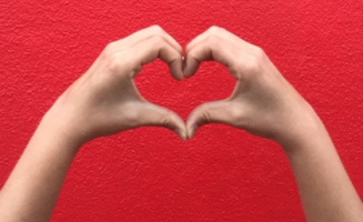 hands making a heart on red background