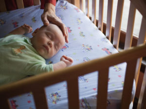 Baby lying on back in crib.
