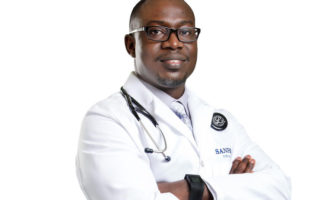 Dr. Steven Boateng in a white coat with arms crossed.