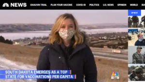 NBC News screen shot with reporter outside Chamberlain, SD, in a face mask ad headline "Covid vaccine couriers deliver doses to rural South Dakota areas, per capita rate one of best in U.S."