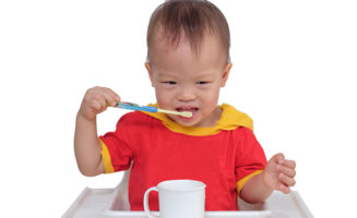 little boy brushes healthy teeth in high chair