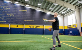 An athlete prepares to throw a football from the turf field inside the Sanford Fieldhouse.