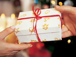 Closeup of a Christmas gift exchange between two people's hands.