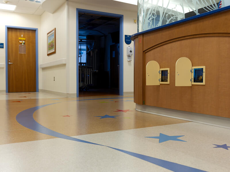 A ribbon and stars decorate the floor of a hospital hallway. Little doors line the wall at child's height.