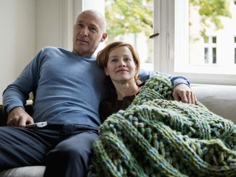 A middle aged couple relaxing on a sofa.