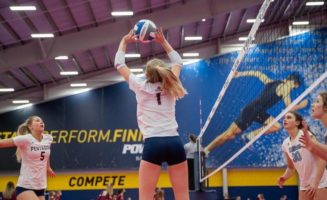 A Sanford Pentagon volleyball player sets the ball above her head for a teammate while opponents watch at the net.