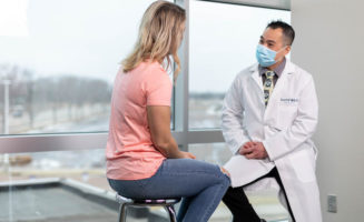 A patient with her back to you talks with her Sanford Health primary care provider.