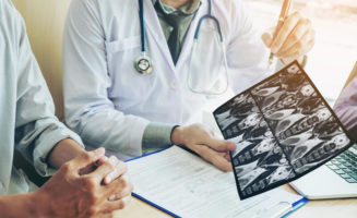 Doctor consulting with patient presenting results on X-ray film about the problem of the patient.