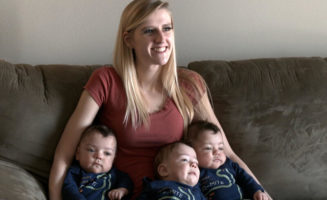 A new mom sits on the couch holding three baby boys - triplets she had while quitting smoking at Sanford Health.