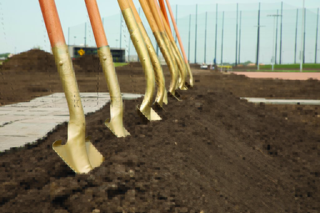 A row of golden shovels stand dug into a dirt mound for the Sanford Virtual Care Center groundbreaking.