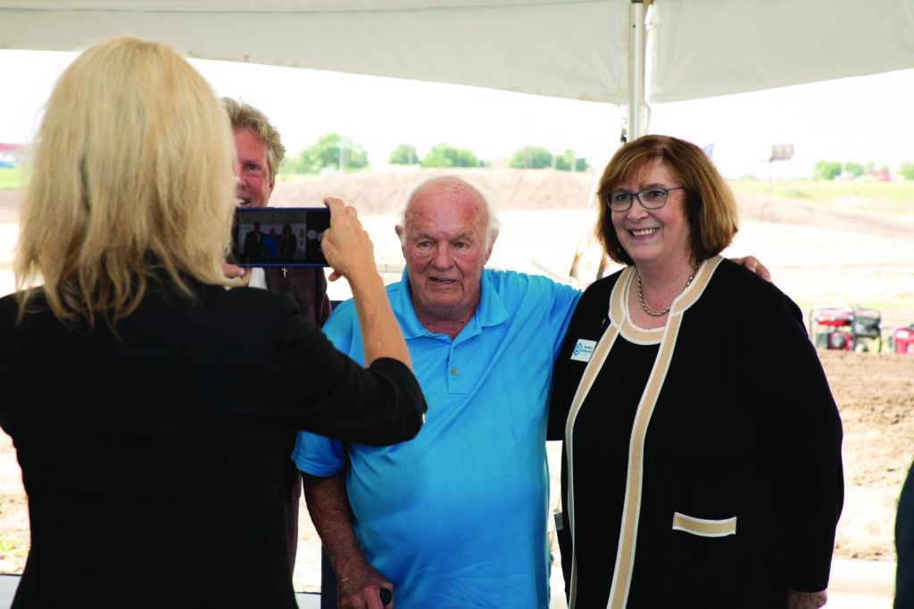 A woman takes a photo of Denny Sanford and two others at the Virtual Care Center groundbreaking.