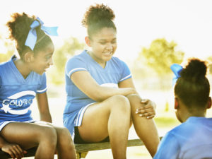 Smiling cheerleaders hanging out together on bleachers after morning workout.