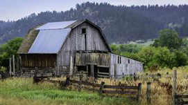 Rustic barn and barnyard with hills in the background.