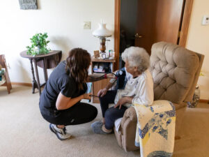 A Good Samaritan nurse uses a blood pressure cuff with a senior woman seated in her living room.