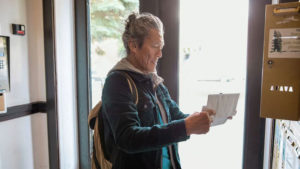 Senior man checks his mailbox in apartment lobby.