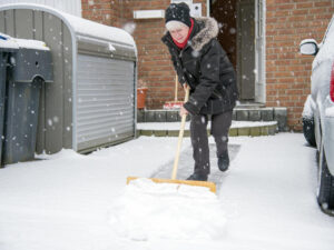 Woman shoveling snow in front of house.