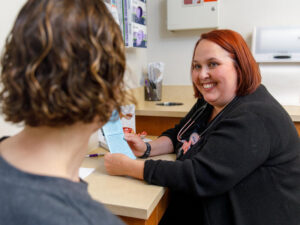 Sanford health care provider smiles at a patient turned toward her in an exam room.