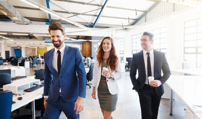 A group of colleagues walking and talking during a coffee break at work.