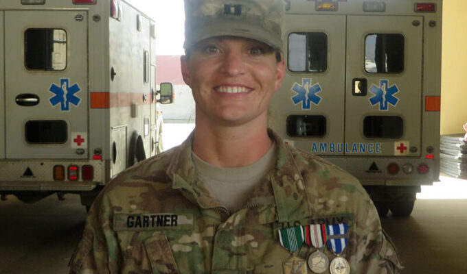 Sanford Health nurse in military uniform smiles in ambulance bay.