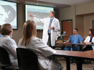 Team of Sanford Health medical providers meet in a conference room. A doctor stands pointing to an image scan on a large screen.