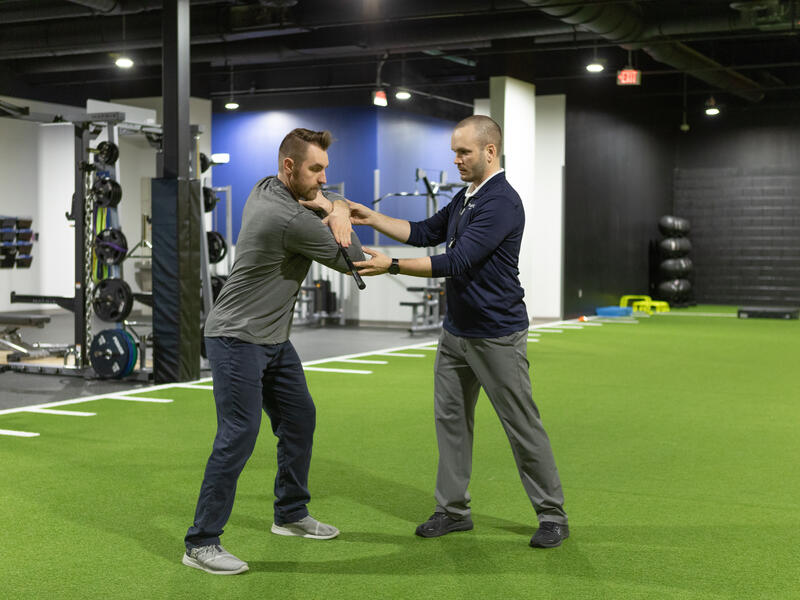 Sanford Sports Performance physical therapist works with a patient on upper body flexibility exercises.