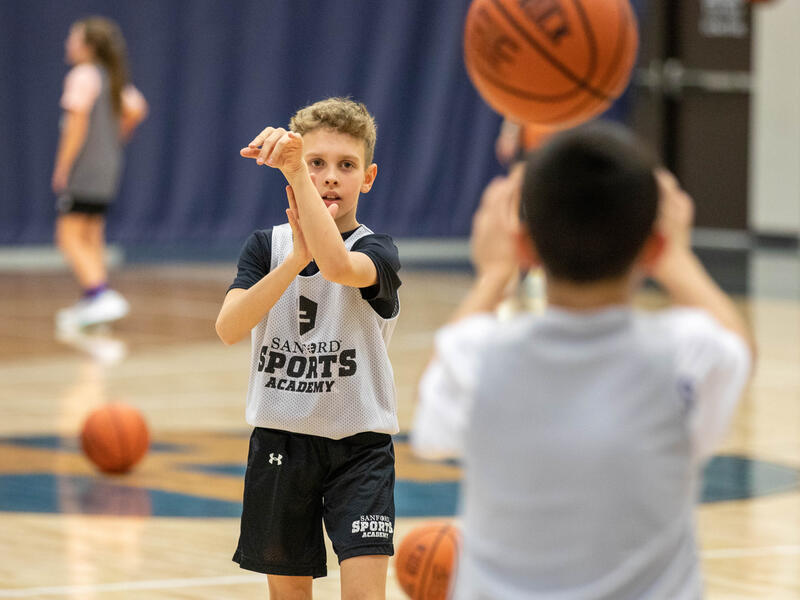 Two school-age boys pass a basketball to each other during Sanford Sports Academy.