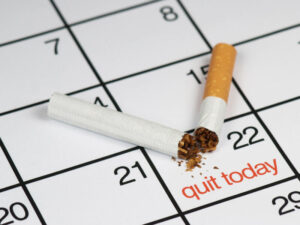 A broken cigarette above a calendar, saying quit today.