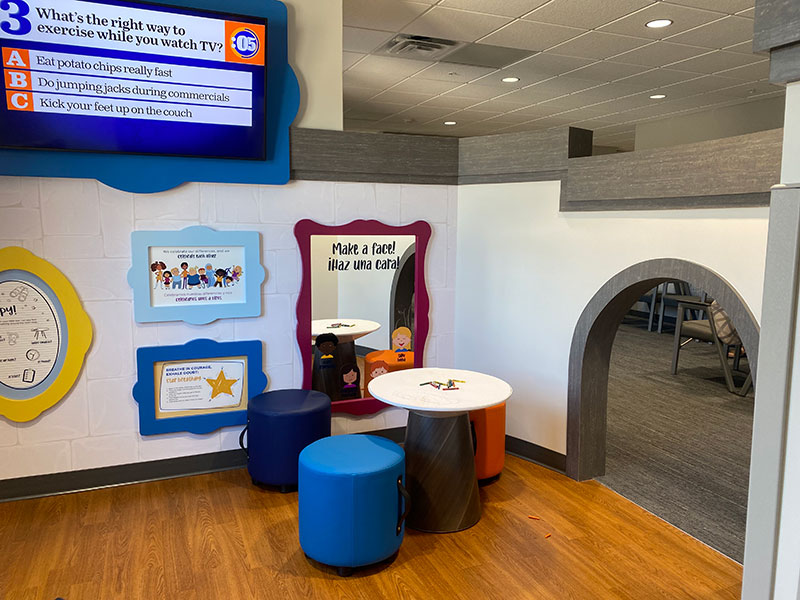 Child-size table, chairs, mirrors and framed trivia questions inside the Sanford Sheldon Clinic waiting room.