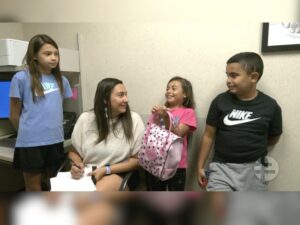 Brittany Nadeau fills out paperwork in an exam room while chatting happily with her son and daughters.