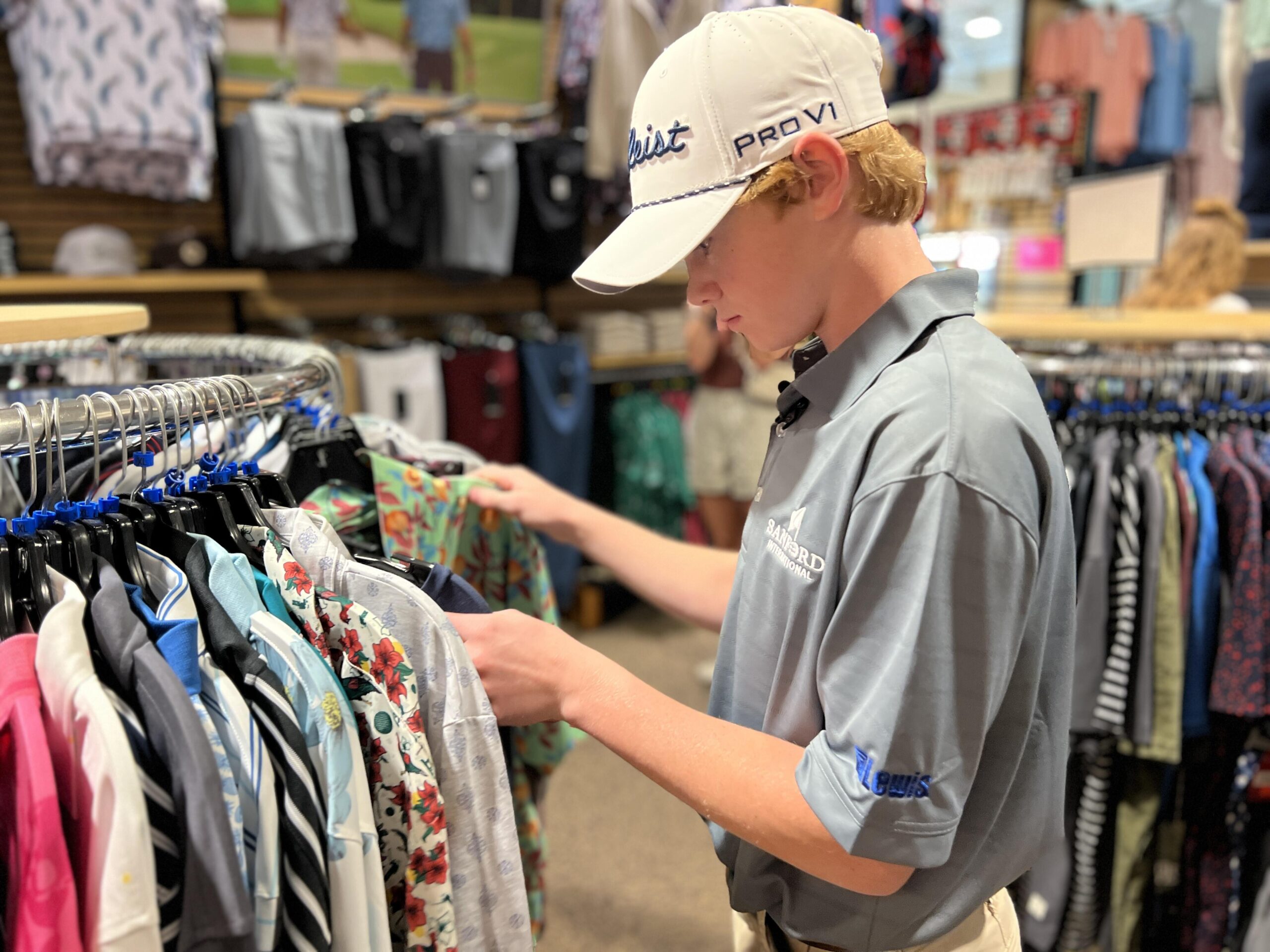 Teen boy sifts through a rack of shirts at a sporting goods store.