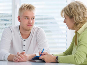 Teenager having a therapy session while therapist is taking notes.