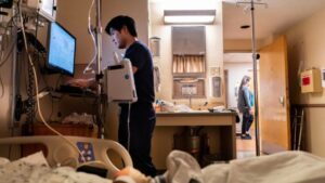 Nurse checks a monitor at a hospital patient's bedside.
