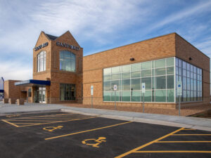 Brick Sanford Health clinic with entrance on left side. Large windows on right side.