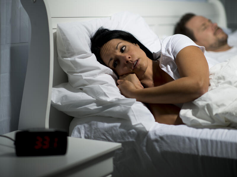 A heterosexual couple in bed unable to sleep.