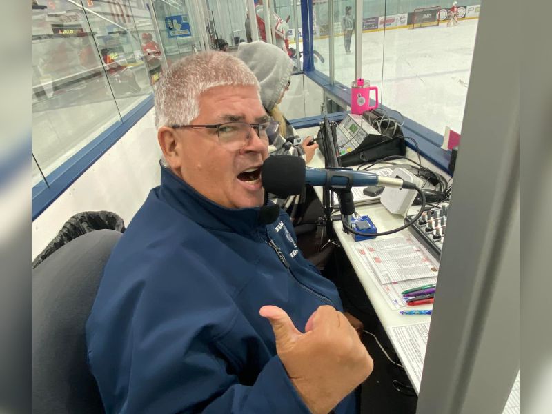 Man behind microphone announcing at hockey game